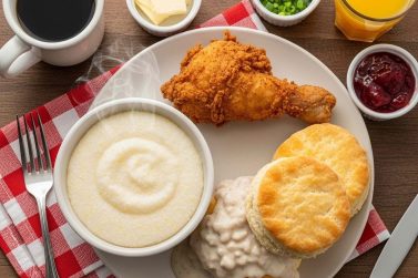 A delicious Southern-style breakfast with fried chicken, biscuits, and grits on a wooden table